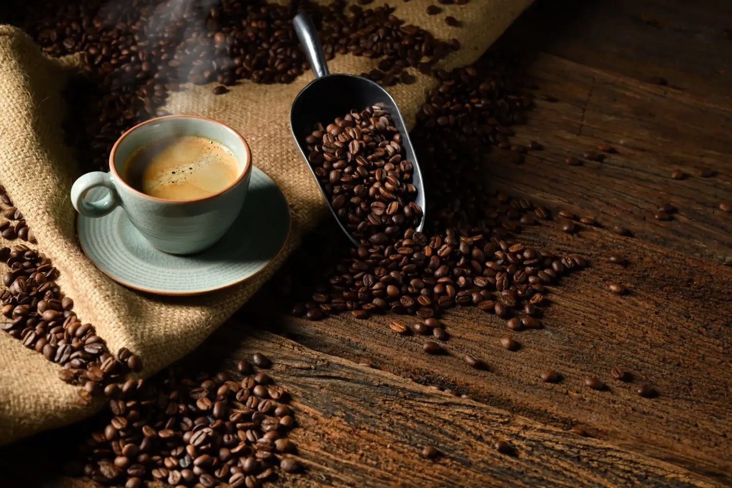 A cup of latte with latte art next to coffee beans.